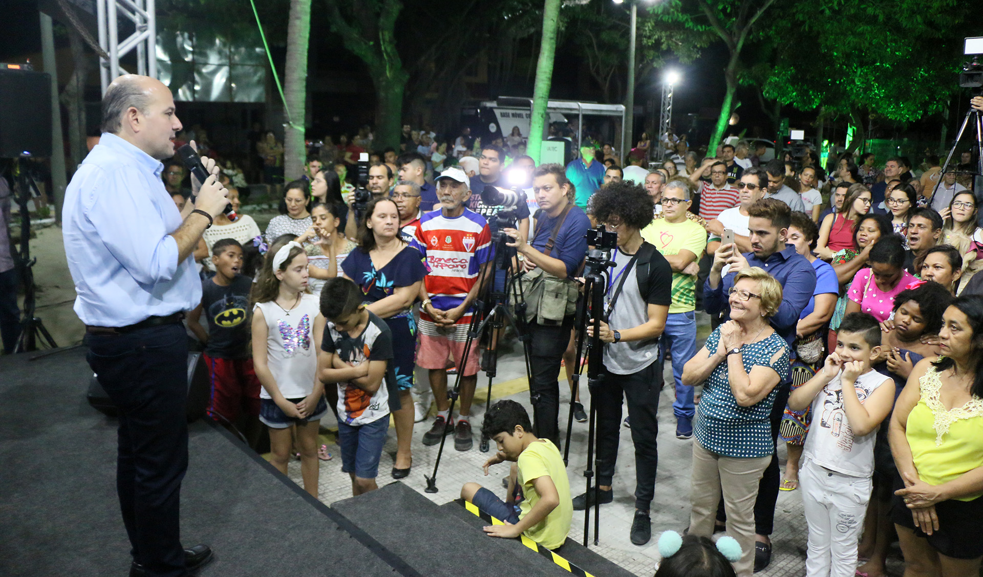 prefeito fala ao microfone em um palco montado na praça